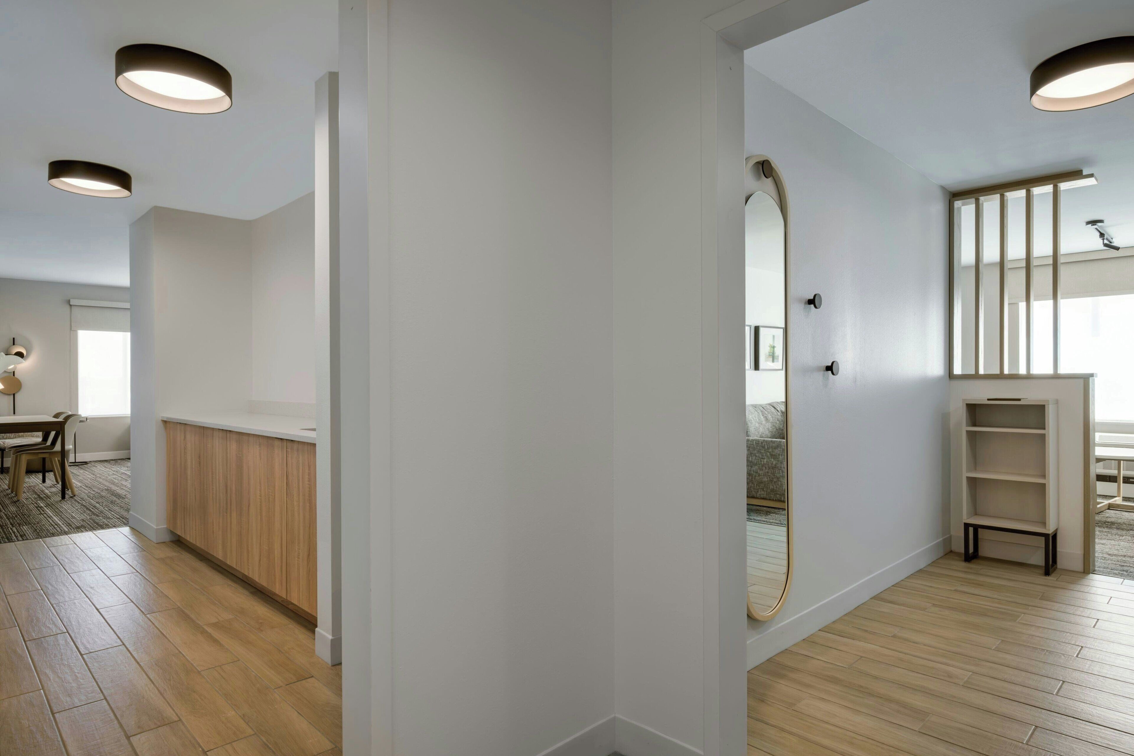 A modern interior with a wooden floor, white walls, and a large mirror.