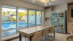 Eine moderne Küche mit einer großen Kochinsel, einem Kühlschrank und Blick auf einen Swimmingpool.
