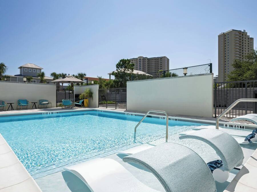 A swimming pool with lounge chairs and a fence.