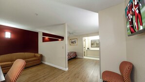 A living room with a sofa, a chair, and a television mounted on the wall.