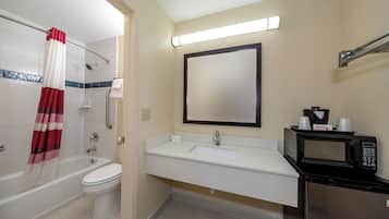 Un baño con bañera, inodoro, lavabo y un microondas.