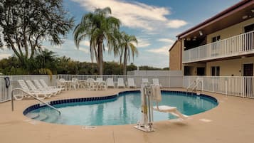 Una piscina al aire libre, sombrillas, sillones reclinables de piscina