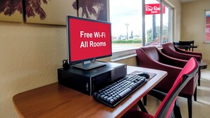 A computer desk with a monitor displaying 'Free Wi-Fi All Rooms' in a hotel room.