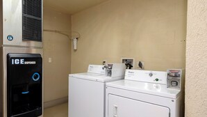 A laundry facility with an ice dispenser and two Whirlpool washing machines.