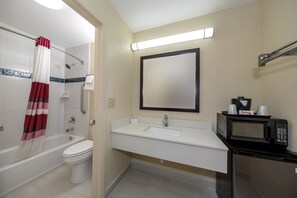 Une salle de bain équipée d’une baignoire, de toilettes, d’un lavabo et d’un four à micro-ondes posé sur le comptoir.