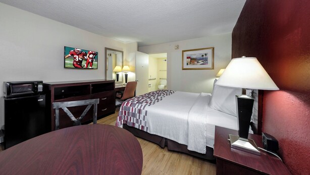 A hotel room with a bed, desk, chair, TV, and a dining table.