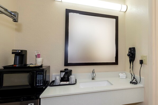 Une salle de bain d’hôtel équipée d’un lavabo, d’un miroir et d’une machine à café.