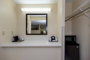A hotel room with a white countertop, a coffee maker, a microwave, and a mirror above the counter. - Red Roof Inn Ellenton – Bradenton NE (Ellenton)