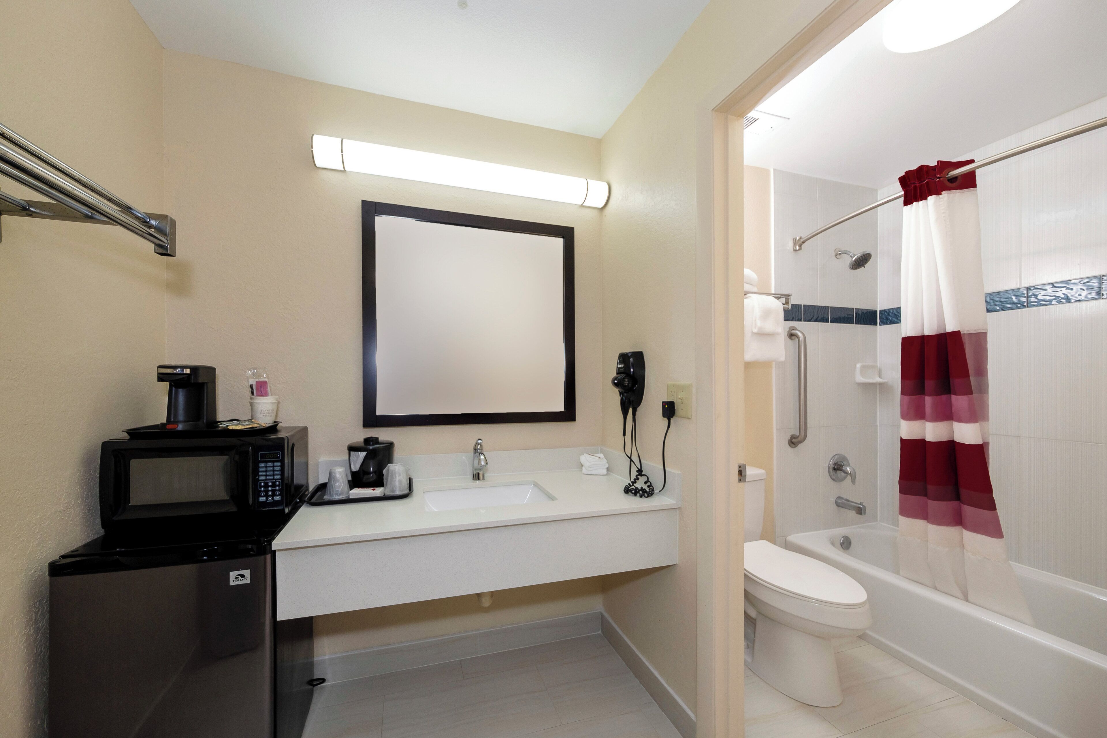 Un baño de hotel con lavabo, inodoro, ducha y espejo.