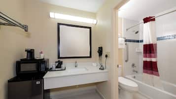 Un baño de hotel con lavabo, inodoro, ducha y espejo.