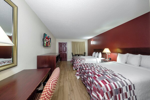 Una habitación de hotel con cama, escritorio, silla, televisor y puerta.