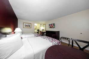 Een hotelkamer met twee bedden, een bureau, een stoel, een televisie en een spiegel.