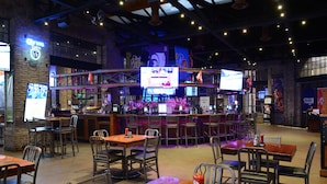 A restaurant with multiple tables and chairs, a bar area, and various decorations including flags and banners.
