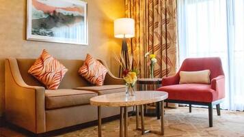 Et hotellobby med en sofa, en lænestol og et rundt bord med en vase med blomster.