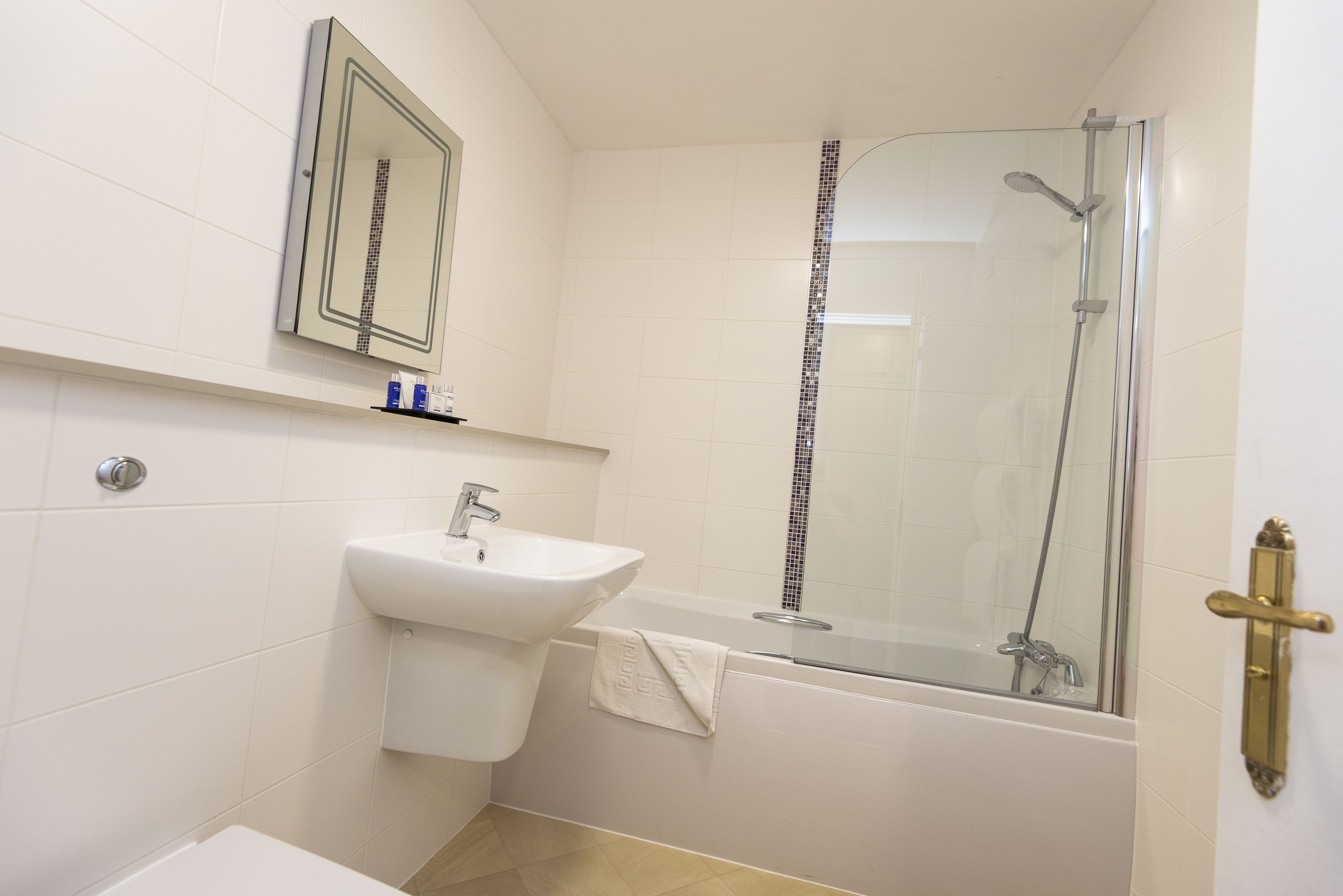 A bathroom with a sink, mirror, and glass-enclosed shower.