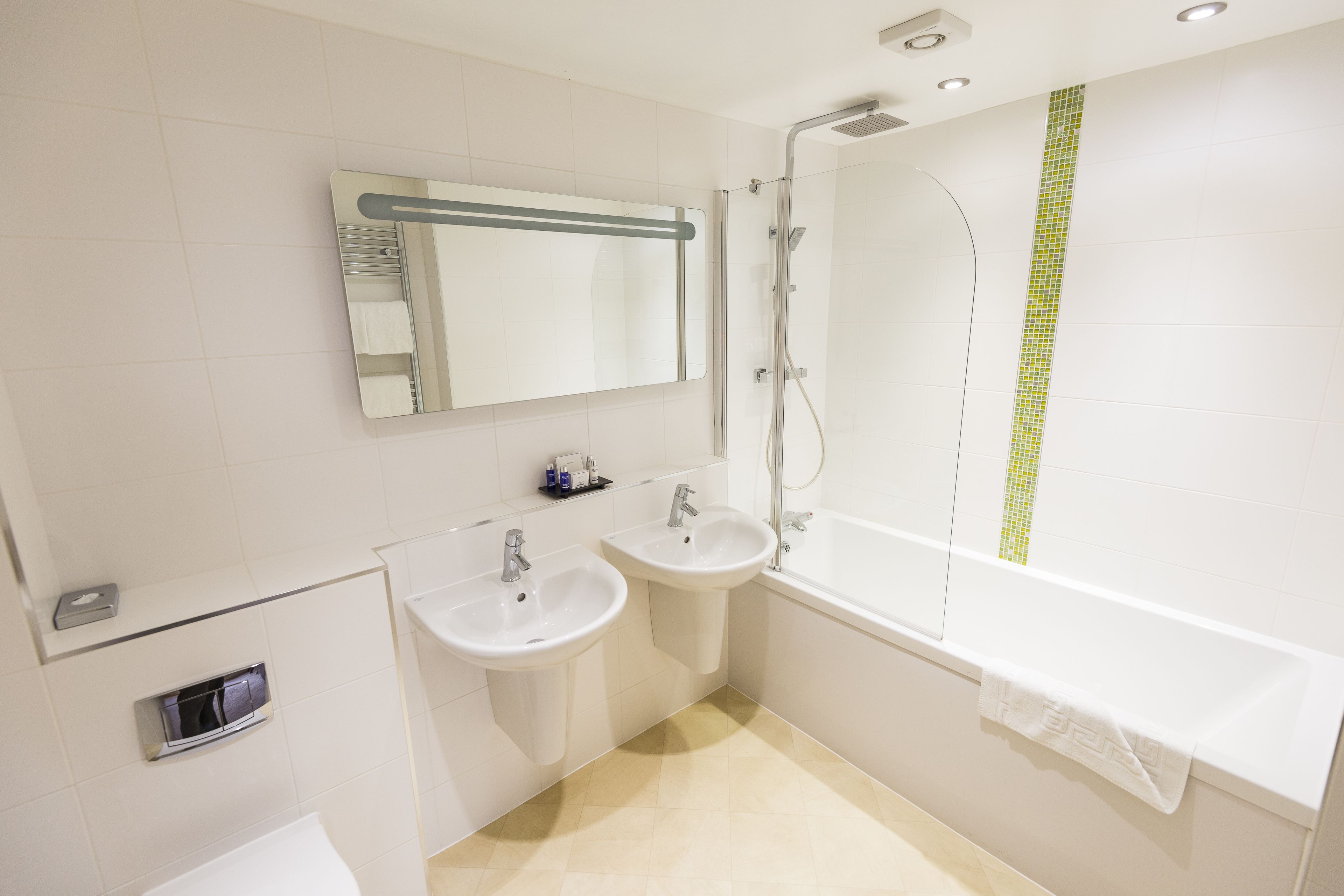 A modern bathroom with two sinks, a bathtub, a shower, and a mirror.