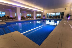 Una piscina techada, sillones reclinables de piscina