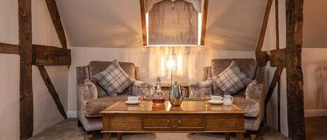 A cozy room with a wooden table, two armchairs, and a decorative mirror.