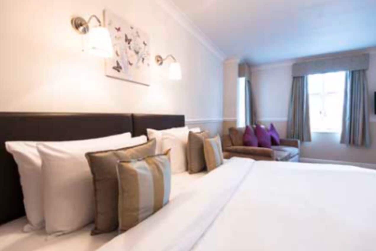 A hotel room with a large bed, a headboard, and a window with curtains.