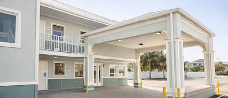 A two-story building with a covered outdoor area, a balcony, and a gated entrance.