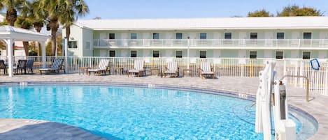 A swimming pool with lounge chairs and a building with multiple windows in the background.