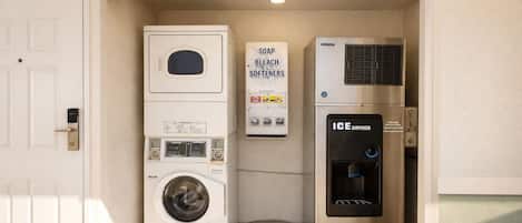 Un cuarto de lavandería con lavadora de carga frontal, dispensador de jabón y lejía, y dispensador de hielo.