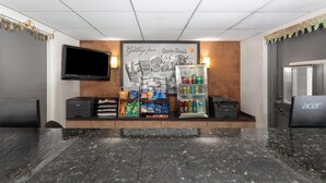Un área de recepción con un televisor de pantalla plana, una máquina expendedora y un refrigerador.