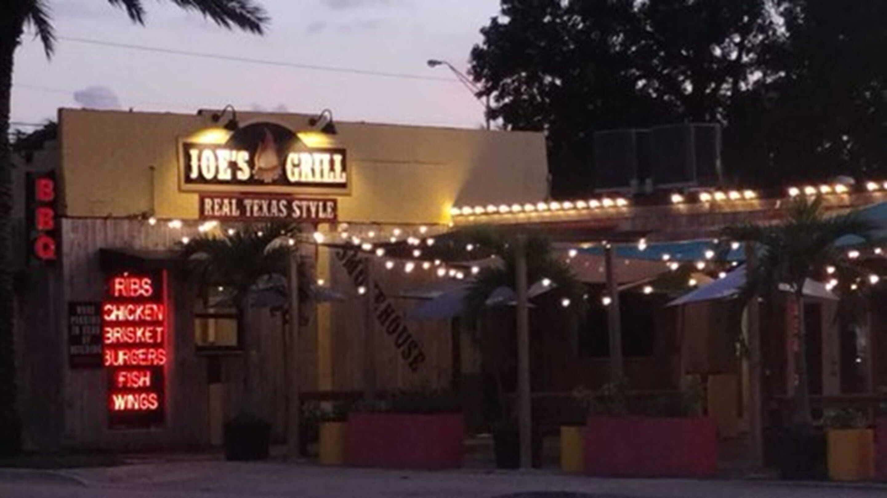 Le Joe's Grill affiche une enseigne indiquant qu'il sert des travers de porc, du poulet, du bœuf braisé, des hamburgers, du poisson et des ailes de poulet.