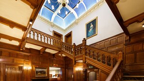 A grand hall with a high ceiling, ornate wooden staircase, and a patterned carpet. - Mercure Bradford, Bankfield Hotel (Bingley)