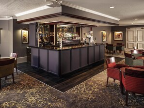 A bar area with a counter, seating, and a patterned carpet. - Mercure Bradford, Bankfield Hotel (Bingley)
