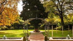 A garden with a metal archway, a bench, and a fountain. - Mercure Bradford, Bankfield Hotel (Bingley)
