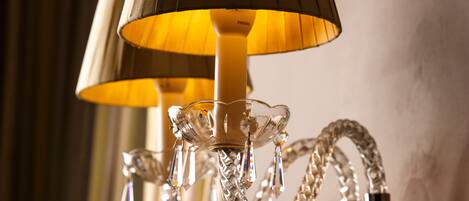 A chandelier with a pleated lampshade and crystal decorations.