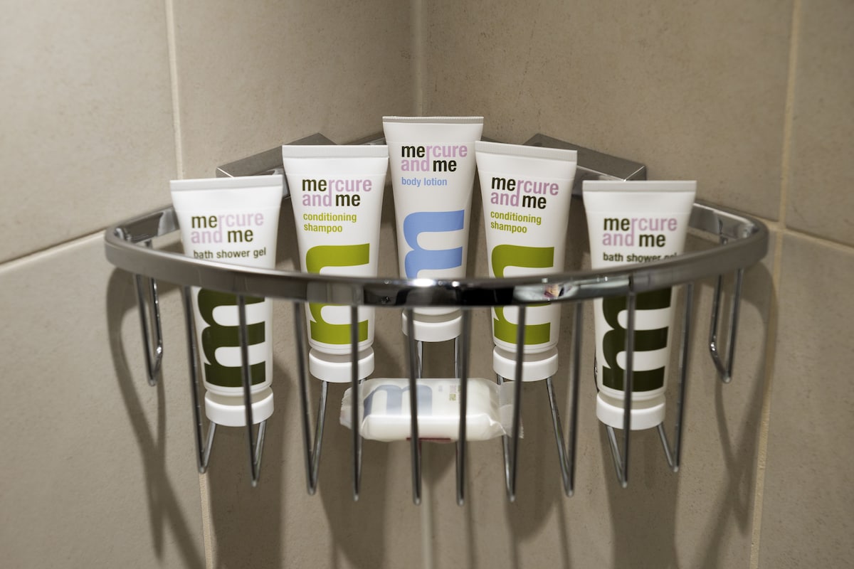 Un portasapone metallico con diversi articoli da bagno, tra cui lozione corpo, shampoo ristrutturante e gel doccia.