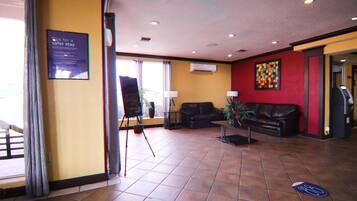 A hotel lobby with a black leather sofa, a standing easel, and a colorful abstract painting on the wall.