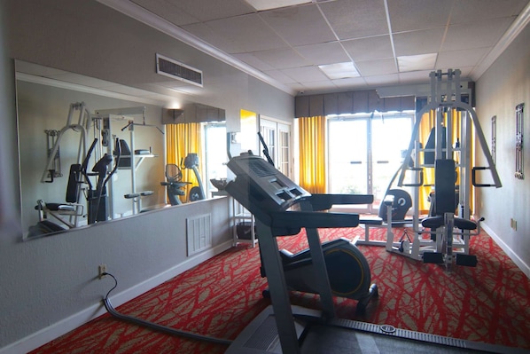 A gym with exercise equipment, a treadmill, and a mirror on the wall.