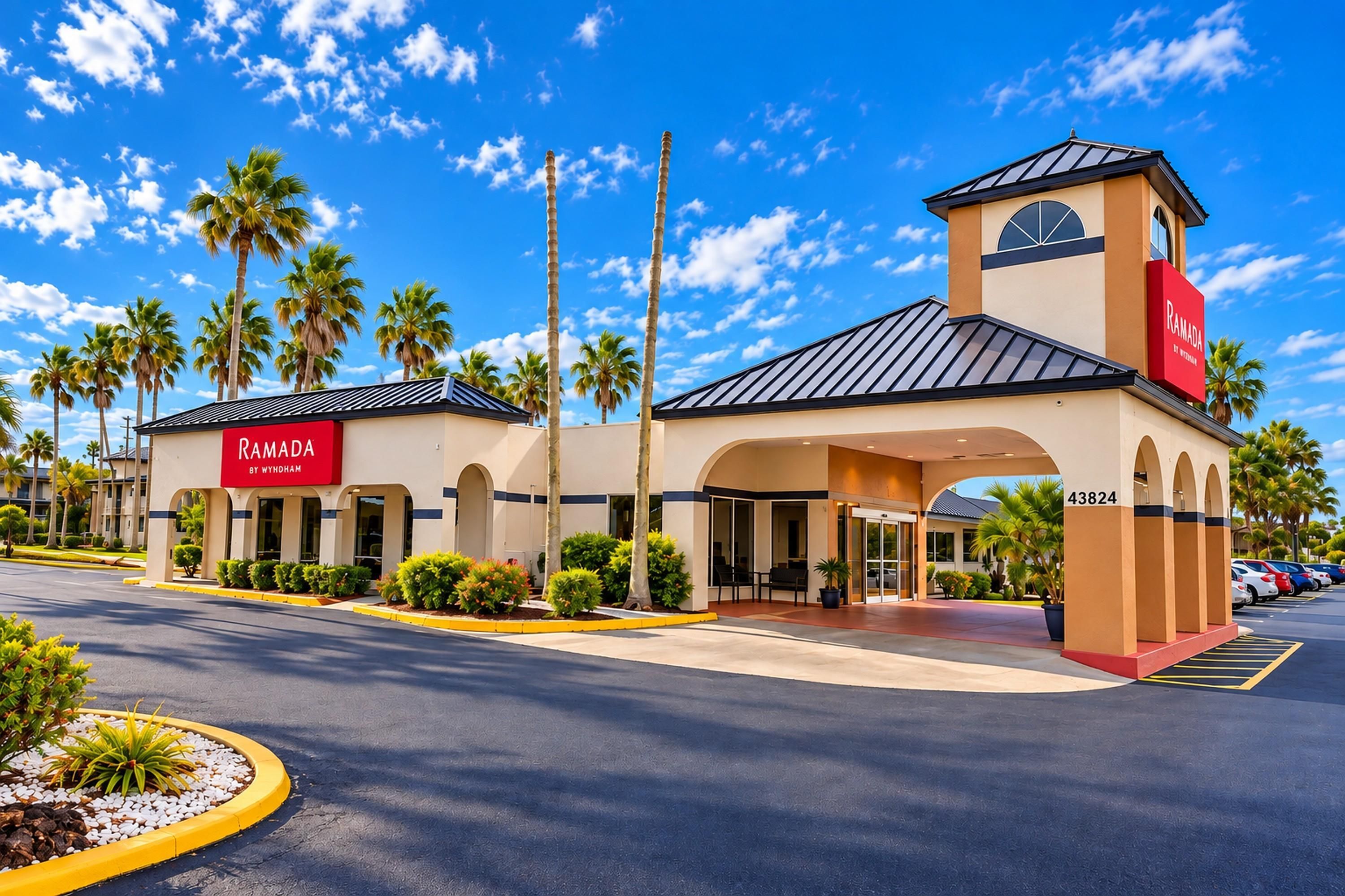 A hotel entrance with a prominent sign, palm trees, and a clear sky.