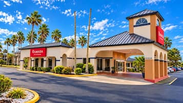 A hotel entrance with a prominent sign, palm trees, and a clear sky.
