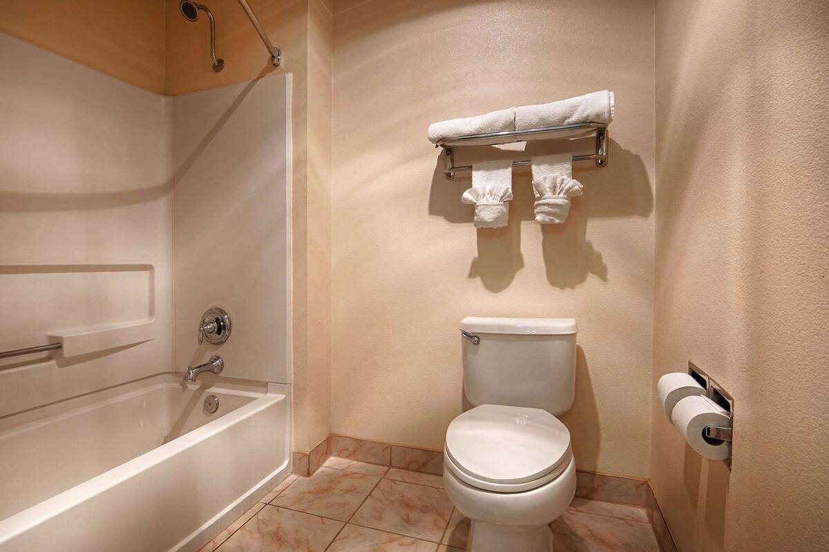 A bathroom with a bathtub, toilet, and towel rack.