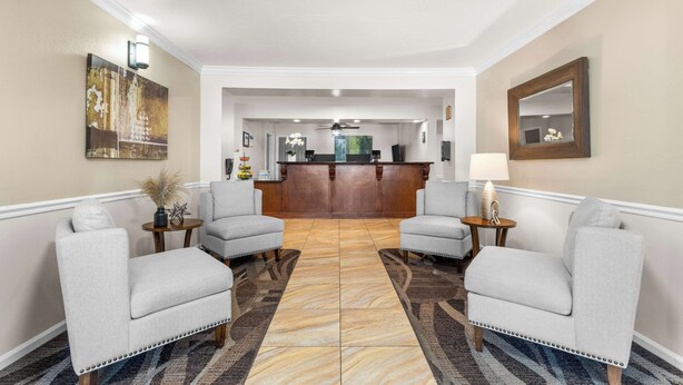 Eine Hotelhalle mit zwei Sesseln, einer Rezeption und einem gemusterten Teppich.