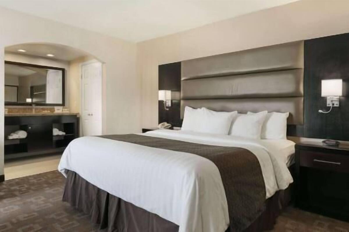 A hotel room with a large bed, a bedside table, a mirror, and a wardrobe.