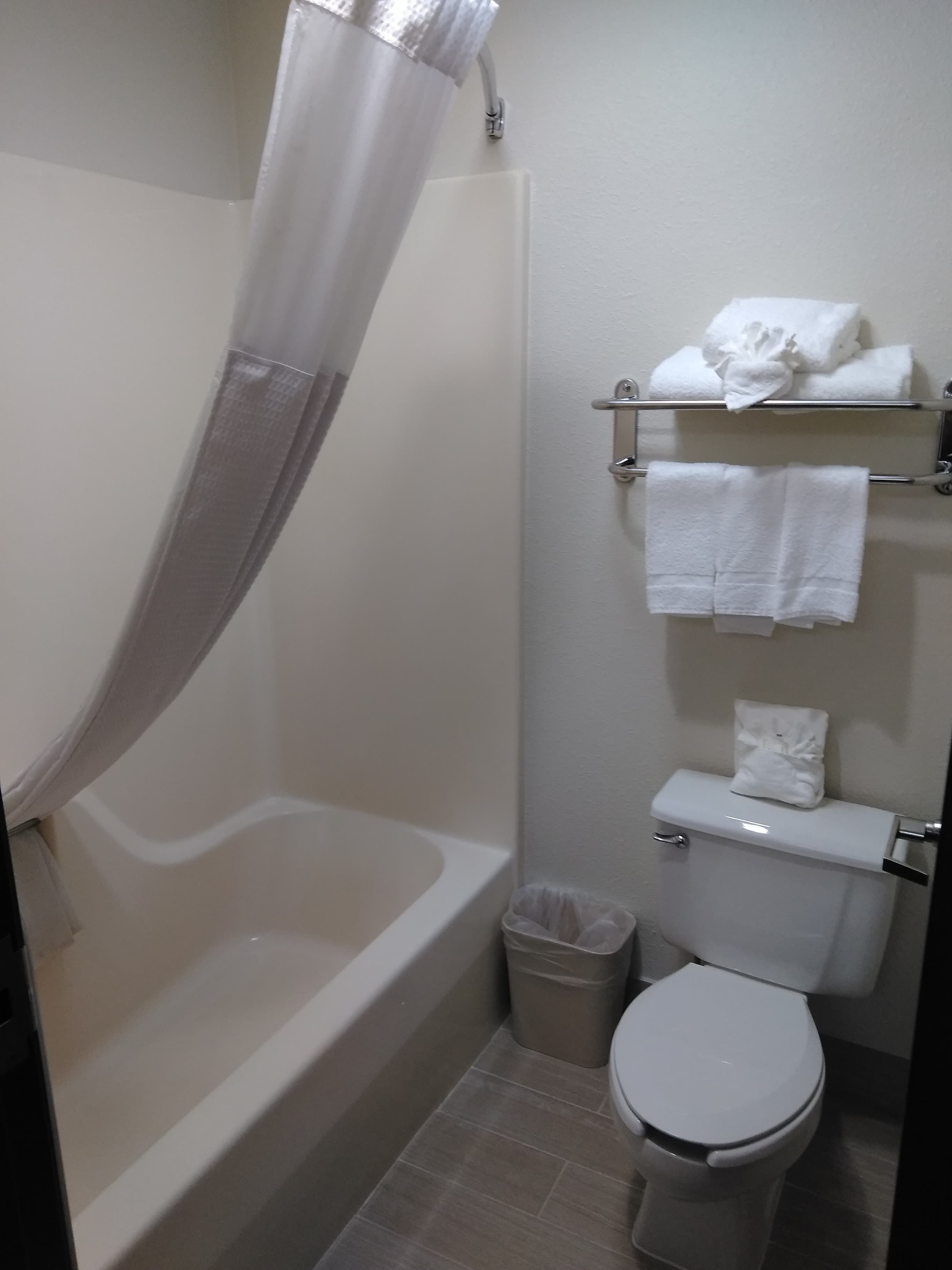 A bathroom with a bathtub, toilet, and a towel rack with towels.