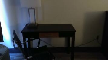 Un petit bureau comprenant un bureau, une chaise et une œuvre d’art encadrée accrochée au mur.