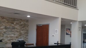 Zona de recepción con pared de piedra, puerta de madera y mostrador negro.