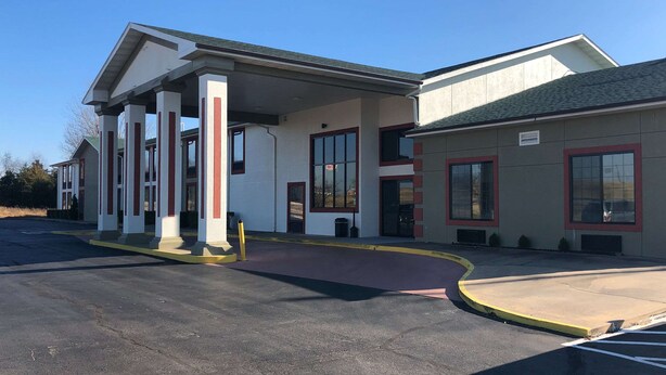 A building with a covered entrance, large windows, and a parking lot.
