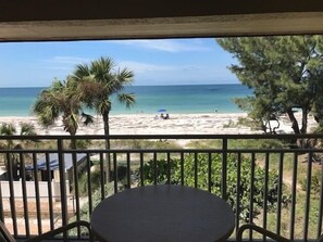 A balcony with a view of a beach, palm trees, and a clear sky. - Club Bamboo South (Bradenton Beach)
