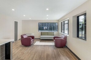A modern room with a wooden floor, a white sofa, and two red armchairs. - Comfort Inn Kansas City Midtown (Kansas City)