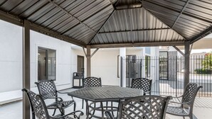 An outdoor patio with a covered seating area, including a table and chairs, and a view of the street and buildings in the background. - Comfort Inn Kansas City Midtown (Kansas City)
