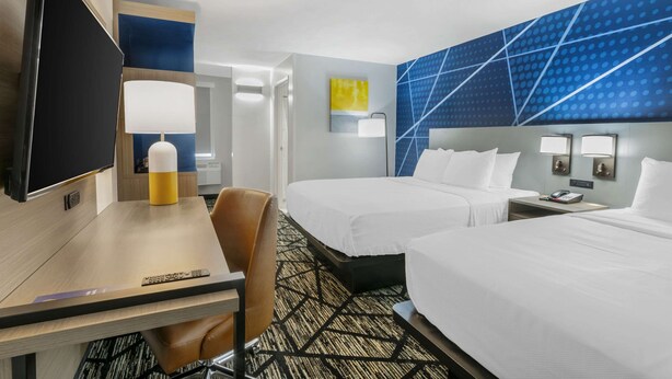 A hotel room with two beds, a desk with a TV, a lamp, and a chair. - Comfort Inn Kansas City Midtown (Kansas City)