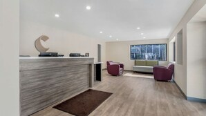 A modern reception area with a grey reception desk, a large window, and two purple chairs. - Comfort Inn Kansas City Midtown (Kansas City)