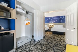 A hotel room with a bed, a desk, a microwave, a mini-fridge, and a wardrobe.